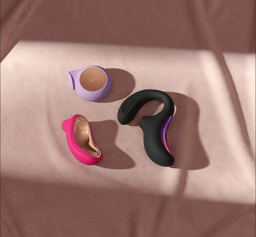 Colorful sex toys including black, pink and purple vibrators displayed on brown fabric