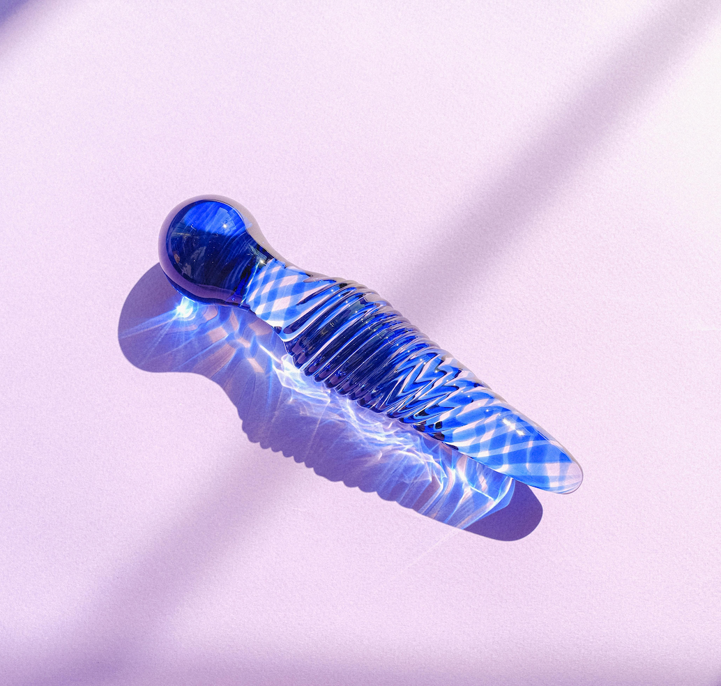 blue glass dildos placed on a purple fabric background