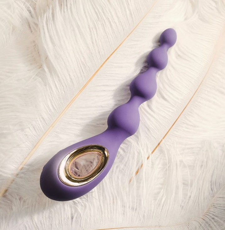Purple anal toy placed on soft white feathers