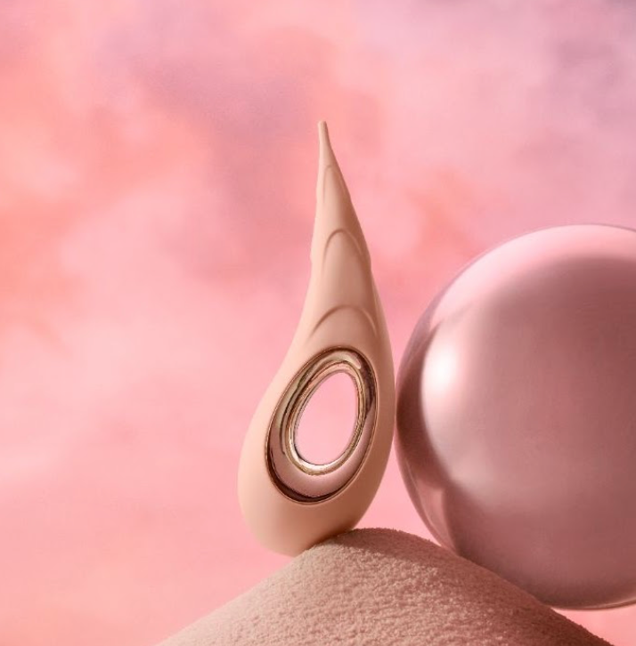 Pink vibrator leaning on a round object with a pink-toned background