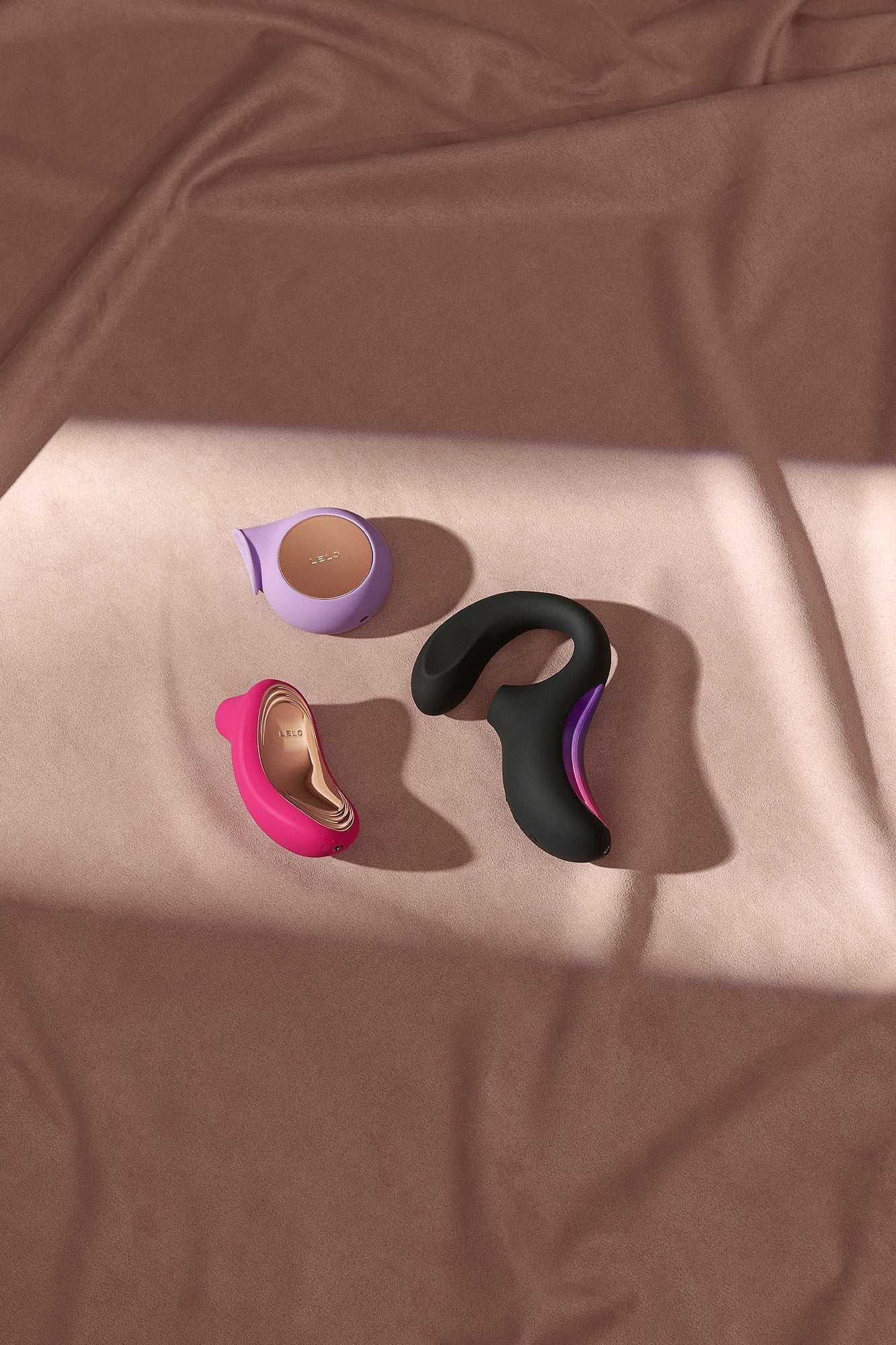 Assorted Kinkkitty sex toys displayed on a brown fabric background in pink, black and purple tones